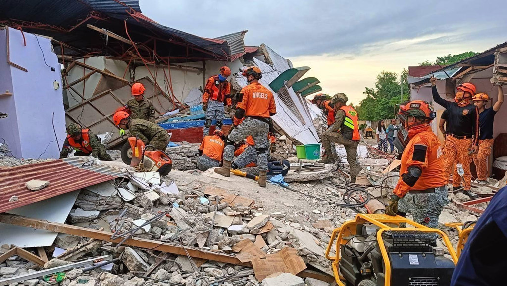 Rescue workers in the Philippines search a building in Bogo City, following the earthquake in Cebu.